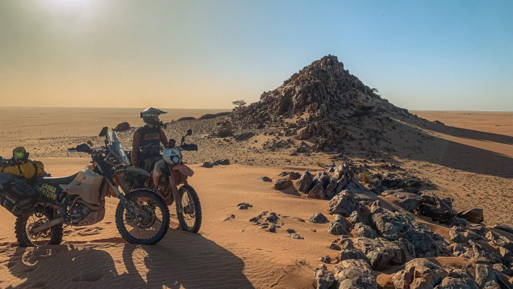 Riders taking a break by a rocky hill in the Mauritanian desert